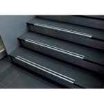 A set of stairs in a building with black railings and Warrior Stair Nosing.
