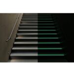 A staircase illuminated by green lighting, enhanced with Warrior Stair Nosing 51MM Height 30MM Width With Glow In Dark Carborundum Tape ASN5130FT for additional safety.