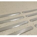 A set of Warrior SS Tactile Strip 35MM Width 280MM Length Pin Type Diamond Top ATS28035SS-D-PIN floor mats on a concrete floor.