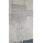 A Warrior SS Tactile Strip 40MM Width 280MM Length Double Sided Linear Top ATS28040SS-LIN-ADH placed on a concrete floor, creating a tactile strip.