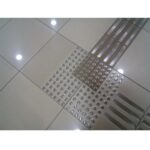 A tile floor with intricate metal strips on it, featuring the Warrior SS Tactile Stud 30MM Dia 4MM Height Double Sided Ring Top ATS30SS-R-ADH design.