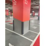 A parking garage with red and white paint on the walls and black Rubber Corner Guards.