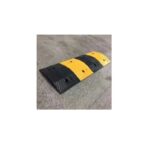 A yellow and black Warrior Rubber Speed Hump 50MM Height 350MM Width 500MM Length RSH35050050 placed on a concrete floor, with a height of 50MM and a length of 500MM.