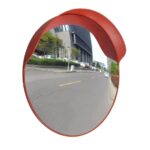 A red circular mirror, specifically the Warrior 100CM Convex Mirror WAR-CM100-PM model from Warrior, placed on the side of the road.