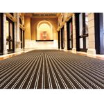 A hallway with a striking black and white striped carpet featuring the Warrior Aluminium Entrance Mat 22MM Height Carpet Insert AEM22A.