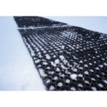 A Warrior Rubber Hollow Mat 22MM Thk 100CM Width 150CM Length Black with holes in it is sitting in the snow.