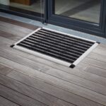 A Warrior Aluminium Entrance Mat 42CM Width 60CM Length Charcoal placed on a wooden deck.